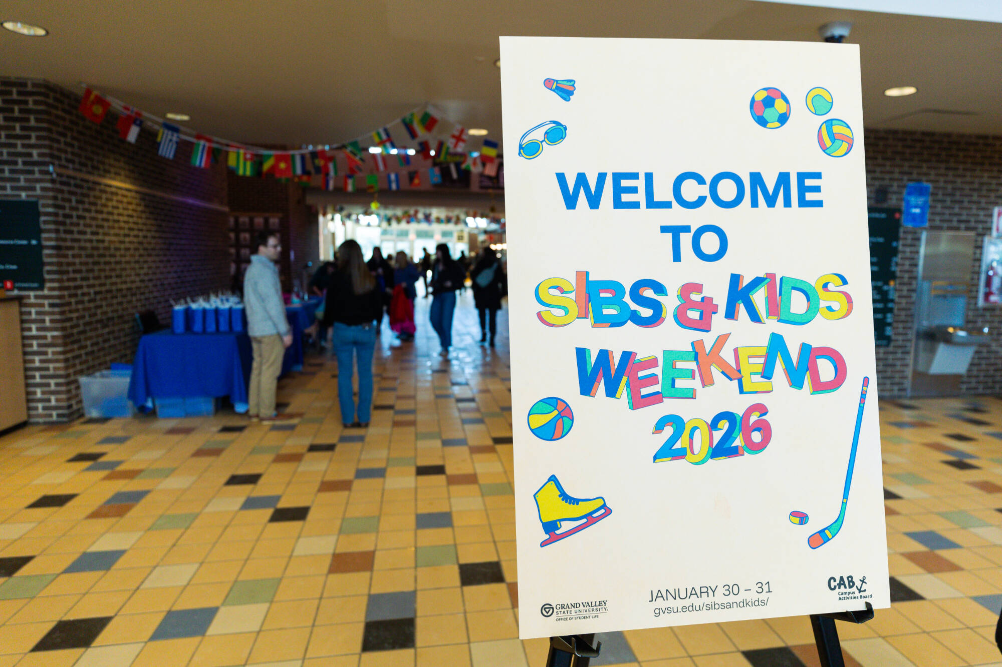 Foam core sign on an easel that says "Welcome to Sibs & Kids Weekend 2026"